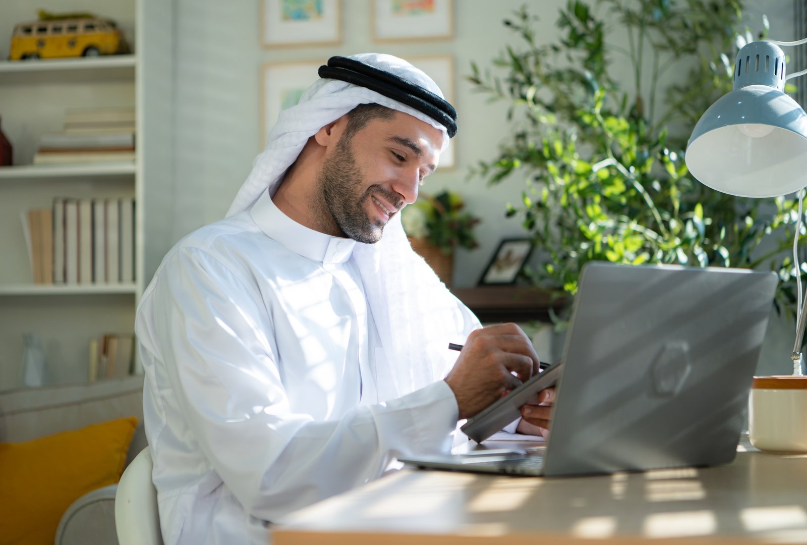 Portrait of young Arabic businessman working on laptop at home